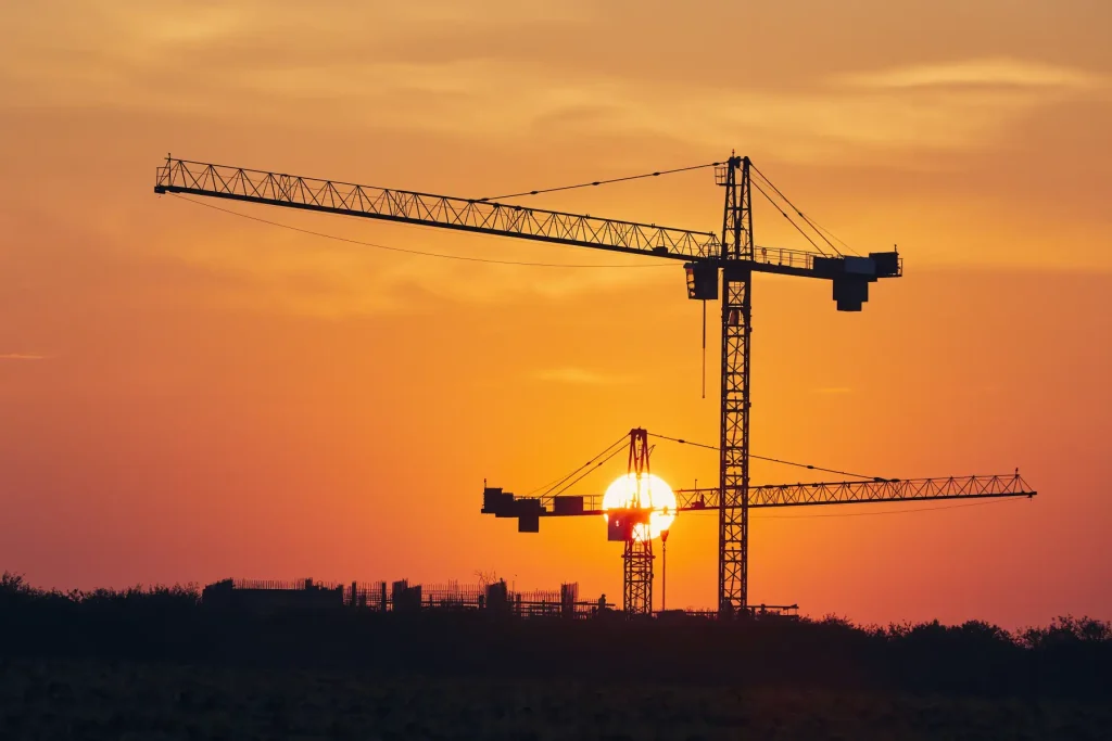 Baukräne vor einem Sonnenuntergang, Symbolbild für den Wohnungsbau 2026