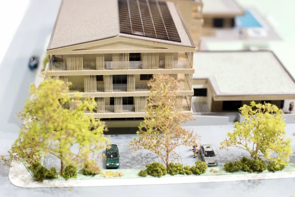 Architekturmodell eines Wohnbaus mit Bäumen und Parkplätzen, Immobilienentwicklung