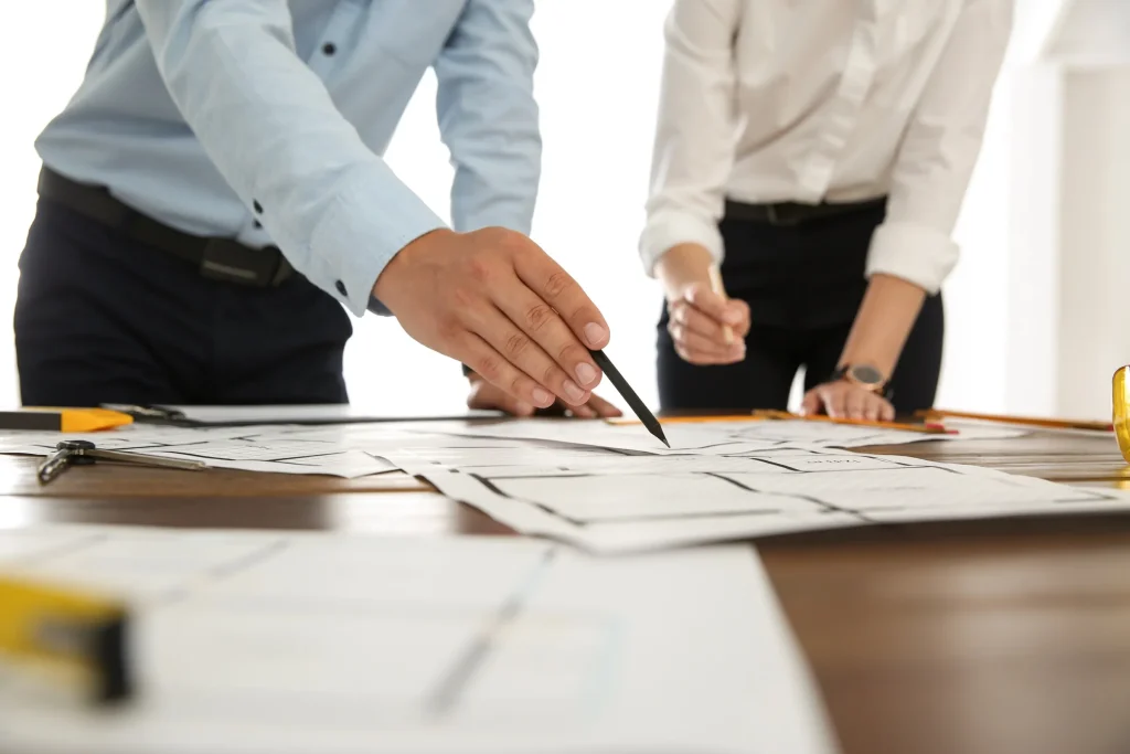 Projektbesprechung an Bauplänen auf einem Holztisch, Projektmanagement