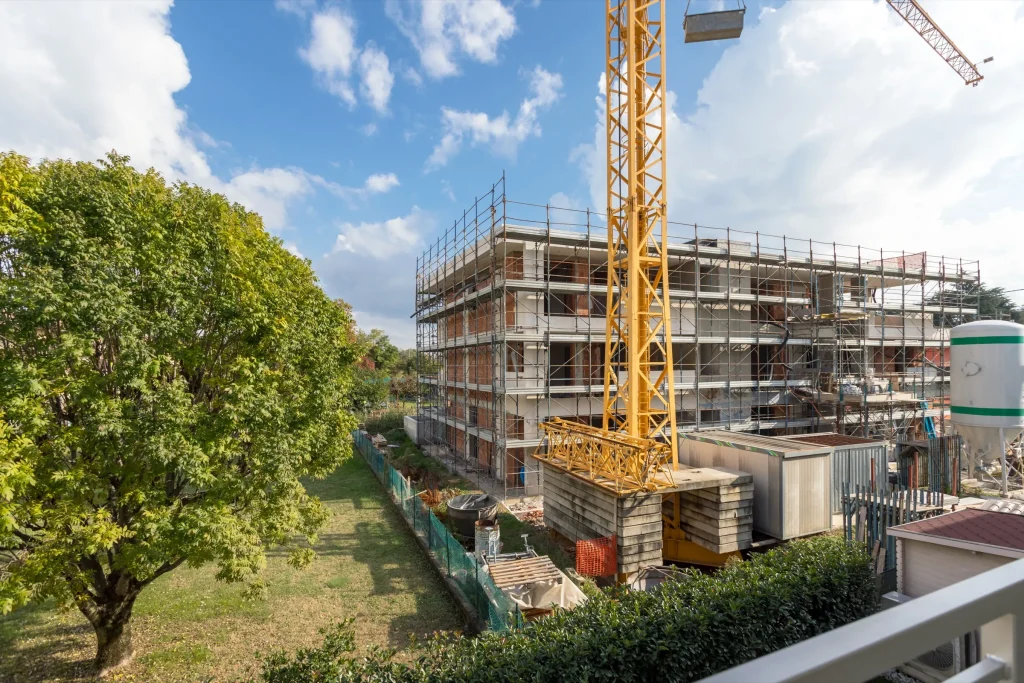 Rohbau eines Mehrfamilienhauses mit Gerüst und Baukran, Totalunternehmung